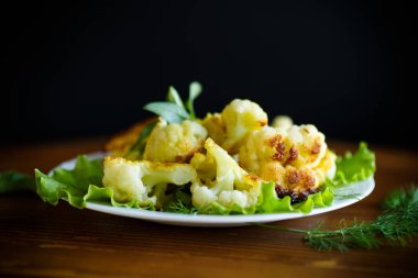 meyilli ahşap bir masa üzerinde bir tabak kızarmış karnabahar