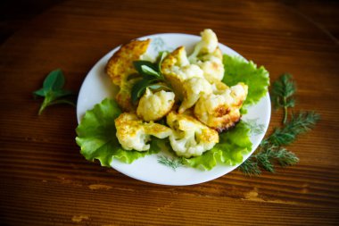 meyilli ahşap bir masa üzerinde bir tabak kızarmış karnabahar