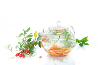 Beyaz arka plan üzerinde izole bir cam çaydanlık Olgun kırmızı goji meyveleri sıcak çay