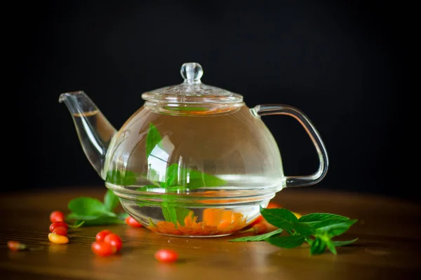 在黑色背景下的玻璃茶壶中 从成熟的红色枸杞中得到的热茶 — 图库照片