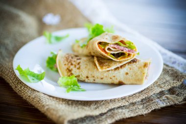salata yaprakları ve ahşap bir masa üzerinde bir tabak içinde pastırma ile ince krep