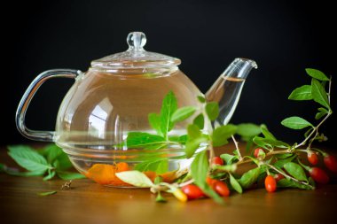 Olgun kırmızı goji meyveleri siyah bir arka plan üzerinde izole bir cam çaydanlık sıcak çay