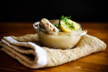 ahşap bir masa üzerinde bir cam kasede balıklı sebze çorbası