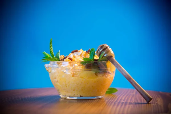 在蓝色背景的玻璃碗里用葡萄干和坚果煮甜南瓜粥 — 图库照片