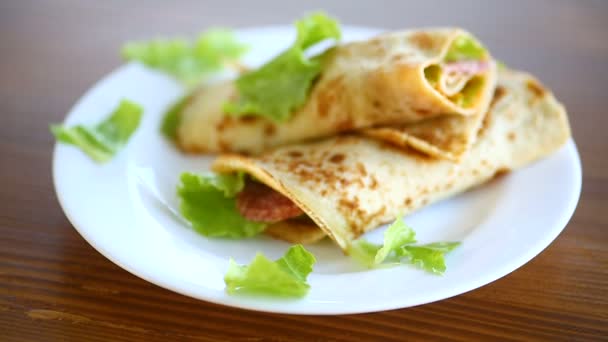 Тонкие блинчики с листьями салата и беконом в тарелке — стоковое видео