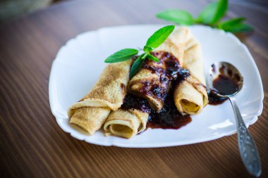 ince kızarmış krep reçel ahşap bir masa üzerinde bir plaka ile doldurulmuş