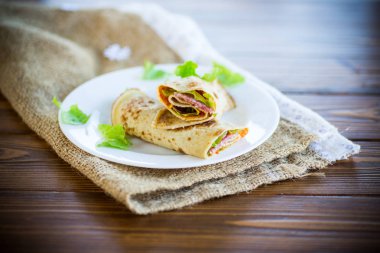 salata yaprakları ve ahşap bir masa üzerinde bir tabak içinde pastırma ile ince krep