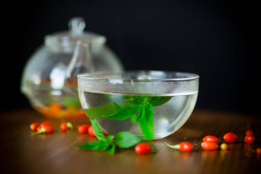 Olgun kırmızı goji meyveleri siyah bir arka plan üzerinde izole bir cam çaydanlık sıcak çay