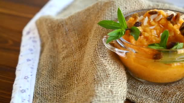 Boiled sweet pumpkin porridge with raisins and nuts in a glass bowl — Stock Video