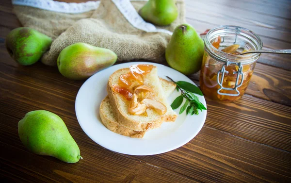 pieces of bread with sweet home-made fruit jam from pears and apples in a plate on a wooden table