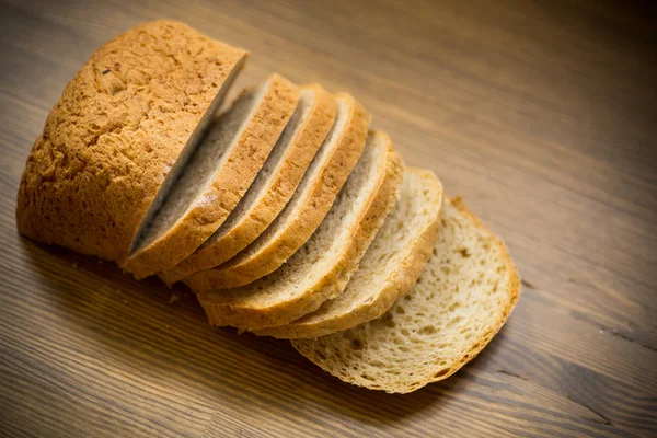 Färskt hembakat bröd skivad på trä bakgrund — Stockfoto