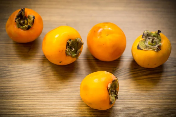 Ripe exotic orange persimmon on wooden background — Stock Photo, Image