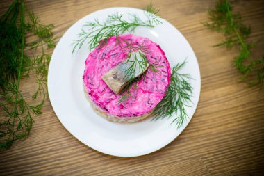 Pancar ve yeşillikleri ile bir tabakta ringa balığı ile haşlanmış sebze salata katmanlı