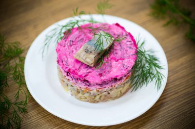 Pancar ve yeşillikleri ile bir tabakta ringa balığı ile haşlanmış sebze salata katmanlı