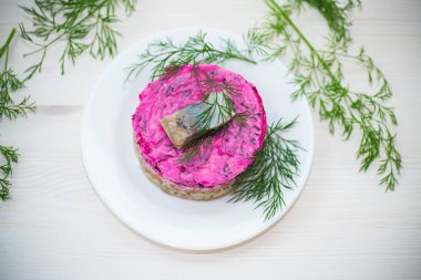 Pancar ve yeşillikleri ile bir tabakta ringa balığı ile haşlanmış sebze salata katmanlı