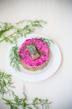 Pancar ve yeşillikleri ile bir tabakta ringa balığı ile haşlanmış sebze salata katmanlı