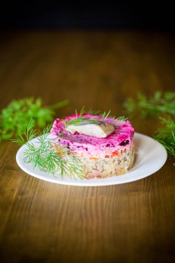 Pancar ve yeşillikleri ile bir tabakta ringa balığı ile haşlanmış sebze salata katmanlı