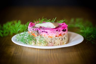 Pancar ve yeşillikleri ile bir tabakta ringa balığı ile haşlanmış sebze salata katmanlı