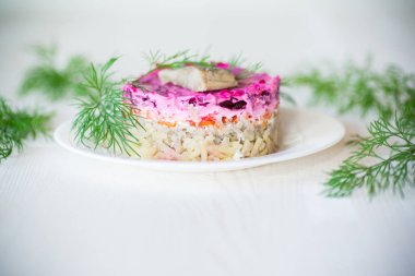 Pancar ve yeşillikleri ile bir tabakta ringa balığı ile haşlanmış sebze salata katmanlı