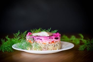 Pancar ve yeşillikleri ile bir tabakta ringa balığı ile haşlanmış sebze salata katmanlı