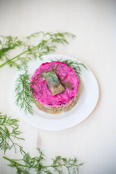 Pancar ve yeşillikleri ile bir tabakta ringa balığı ile haşlanmış sebze salata katmanlı