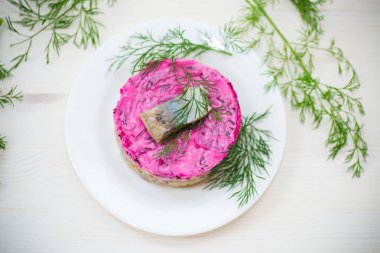 Pancar ve yeşillikleri ile bir tabakta ringa balığı ile haşlanmış sebze salata katmanlı