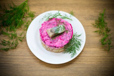 Pancar ve yeşillikleri ile bir tabakta ringa balığı ile haşlanmış sebze salata katmanlı