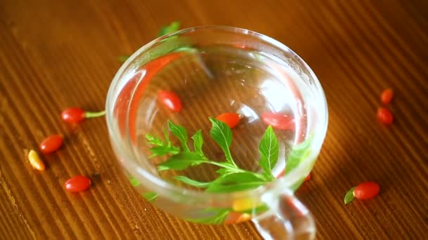heißer Tee aus reifen roten Goji-Beeren in einer gläsernen Teekanne auf einem Holztisch