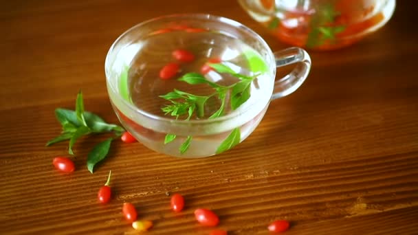 Thé chaud de baies de goji rouges mûres dans une théière en verre — Video