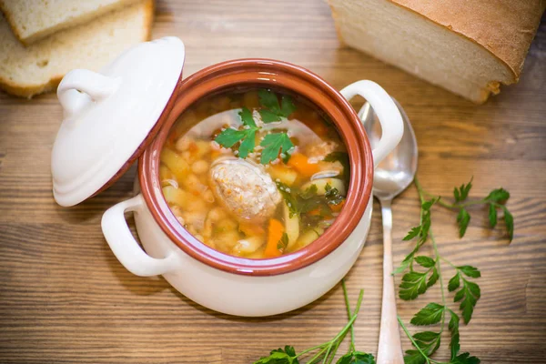 豆と白い木製のテーブル上にセラミック ボウルにミートボールと野菜のスープ — ストック写真