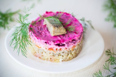 Pancar ve yeşillikleri ile bir tabakta ringa balığı ile haşlanmış sebze salata katmanlı