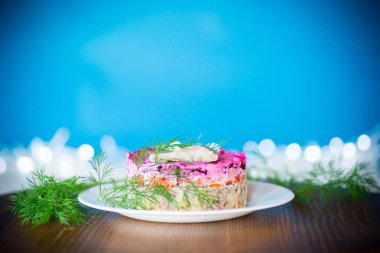 Pancar ve yeşillikleri ile bir tabakta ringa balığı ile haşlanmış sebze salata katmanlı