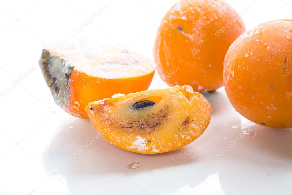 frozen ripe persimmon in ice isolated on white background
