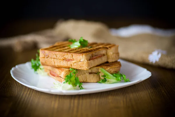 Horké dvojí sendvič s hlávkovým salátem listy a nacpal si do talíře — Stock fotografie