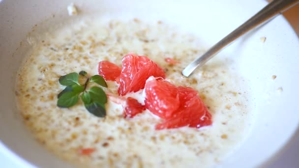 Sweet oatmeal with slices of red grapefruit in a ceramic bowl — Stock Video