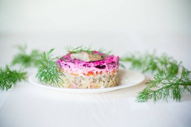 Pancar ve yeşillikleri ile bir tabakta ringa balığı ile haşlanmış sebze salata katmanlı