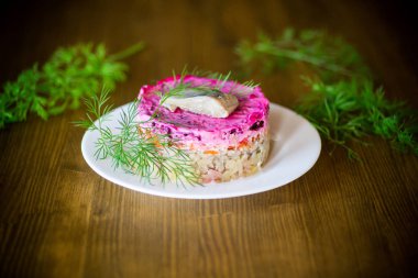 Pancar ve yeşillikleri ile bir tabakta ringa balığı ile haşlanmış sebze salata katmanlı