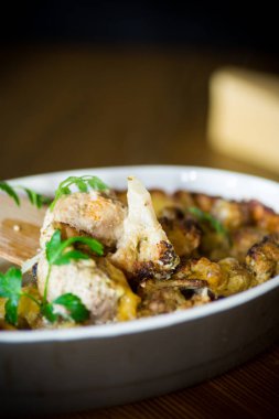 Ahşap bir masa seramik formunda peynir soslu köfte ile karnabahar fırında.