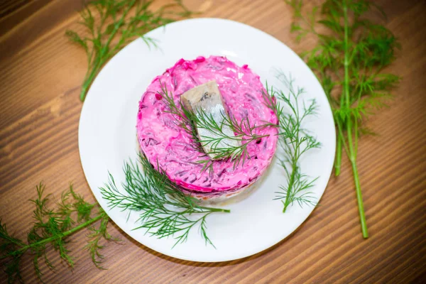 Pancar ve yeşillikleri ile bir tabakta ringa balığı ile haşlanmış sebze salata katmanlı