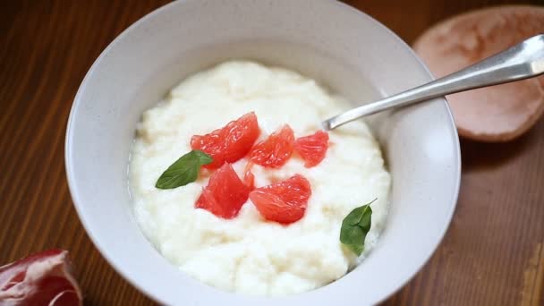 Dolce porridge di semola bollito in un piatto con fette di pompelmo rosso — Video Stock