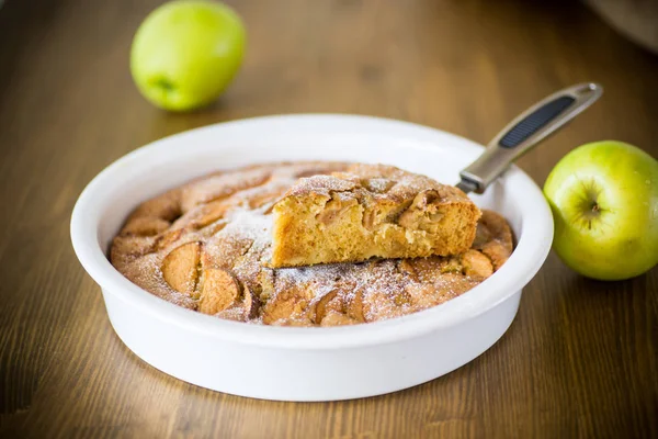 sweet apple pie in ceramic form on a wooden