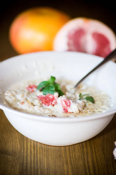 Sweet oatmeal with slices of red grapefruit in a ceramic bowl — Stock Photo, Image