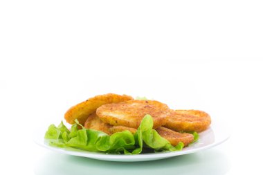 beyaz bir arka plan üzerine bir tabak içinde marul yaprakları ile patates pancakes