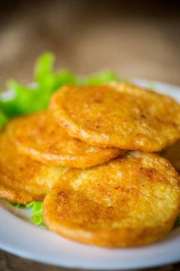 ahşap bir masa üzerinde bir tabak içinde marul yaprakları ile patates pancakes