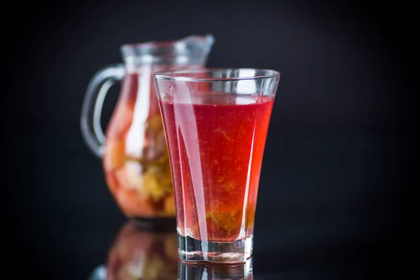 Compota de frutas vermelhas em um decantador com um copo — Fotografia de Stock