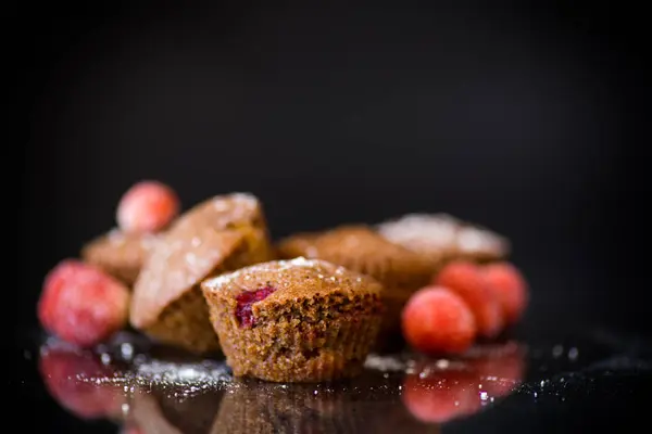 Свежие сладкие кексы с ягодами внутри на черном — стоковое фото