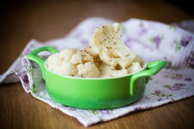 ahşap bir masa üzerinde bir kase içinde baharatlar ile haşlanmış karnabahar