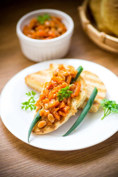 Tostadas de pan frito con frijoles guisados y verduras en un plato —  Fotos de Stock