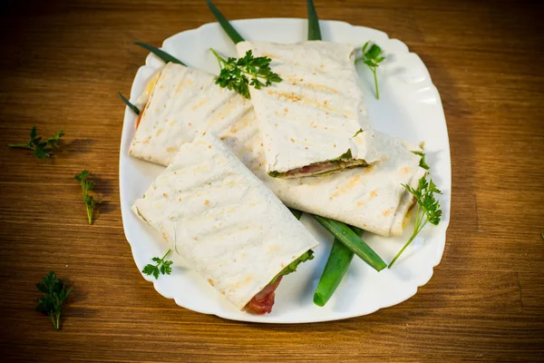 Rouleau de pita aux feuilles de laitue, légumes verts et saucisses dans une assiette — Photo