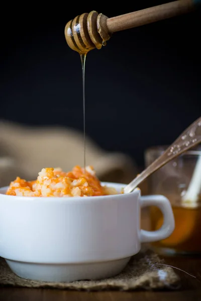 Sweet boiled pumpkin porridge with rice in a plate on a wooden — Stock Photo, Image
